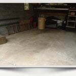 A mostly empty garage with a concrete floor, wooden shelves along the back wall, a brown chest, a plastic container, and some tools—perfect for anyone seeking junk removal in Essex County NJ.